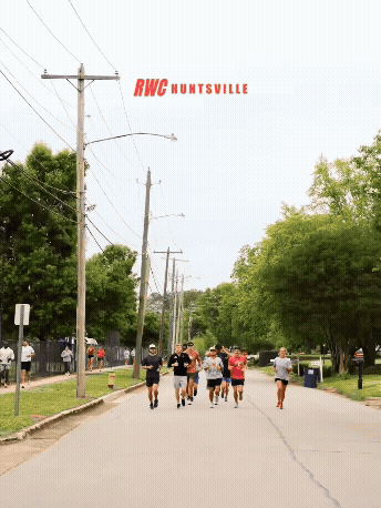 A animation of a group of people jogging or walking on a residential street with trees on either side and utility poles. A sign reads RWC Huntsville.