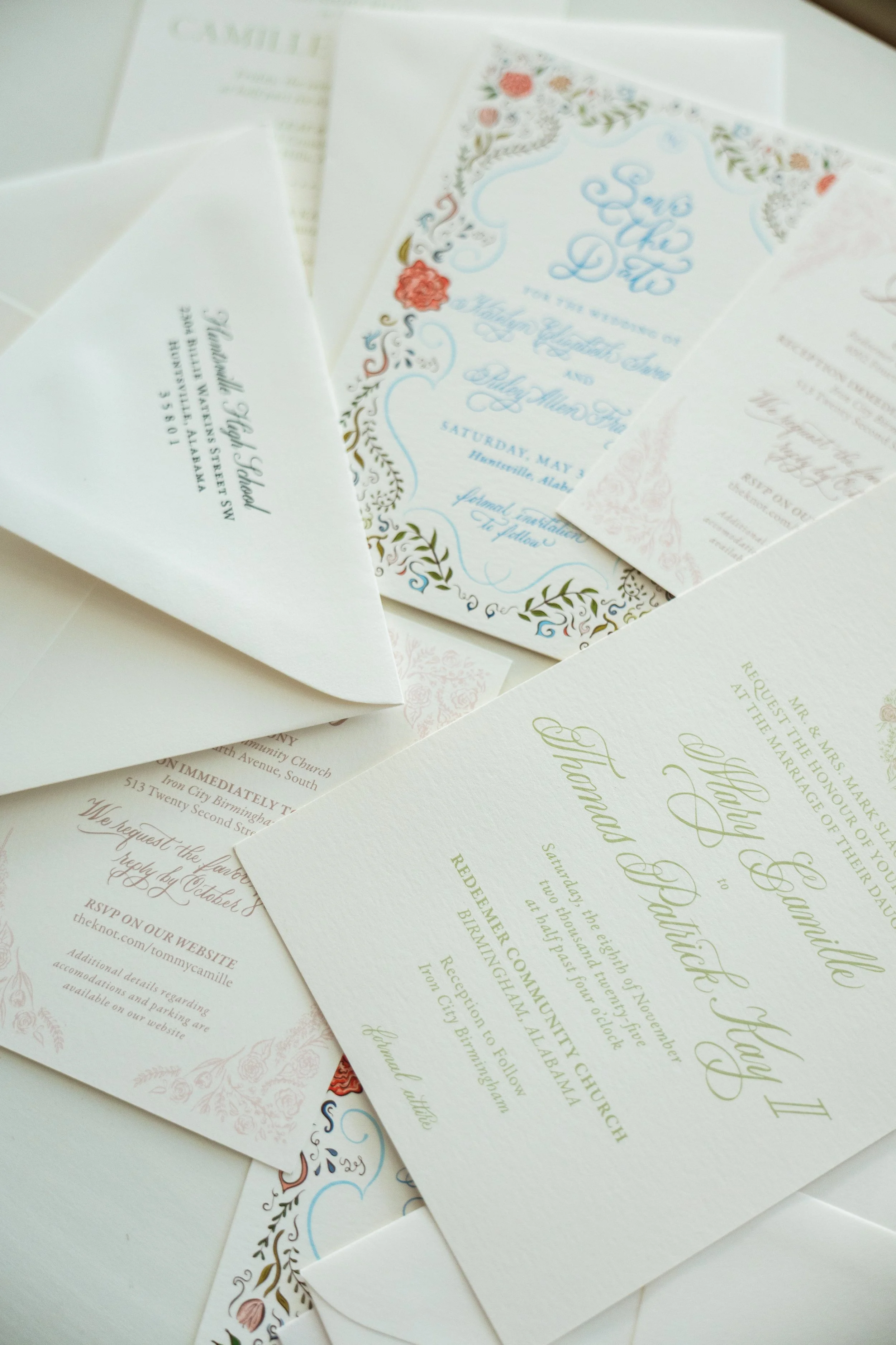 Multiple wedding invitations and envelopes spread out, with some featuring floral designs and decorative lettering.