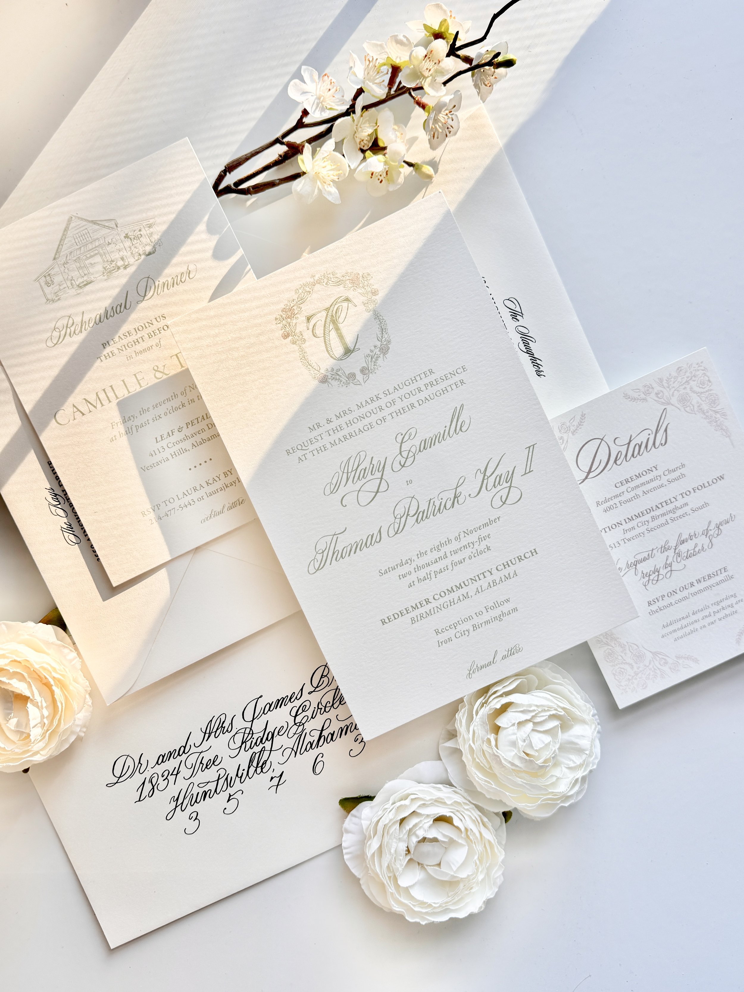Elegant wedding invitations with floral accents and a branch of white blossoms.