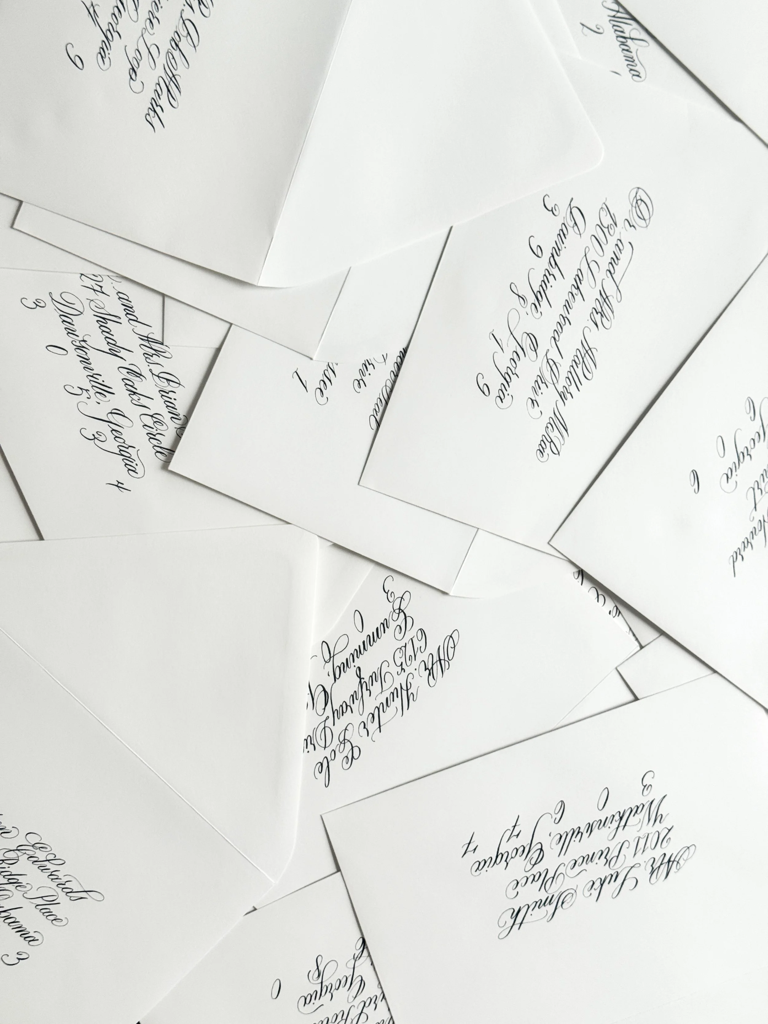 Several pieces of white paper with elegant, cursive handwritten text scattered on a surface.