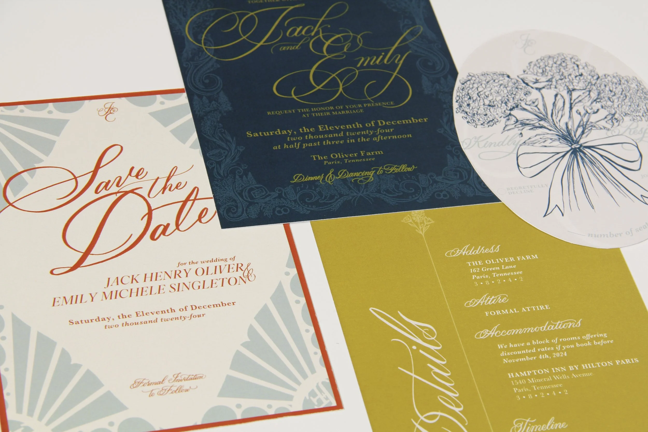 Close-up of wedding invitations with elegant script fonts and gold, blue, and white colors. The visible details include wedding date, names, and address.