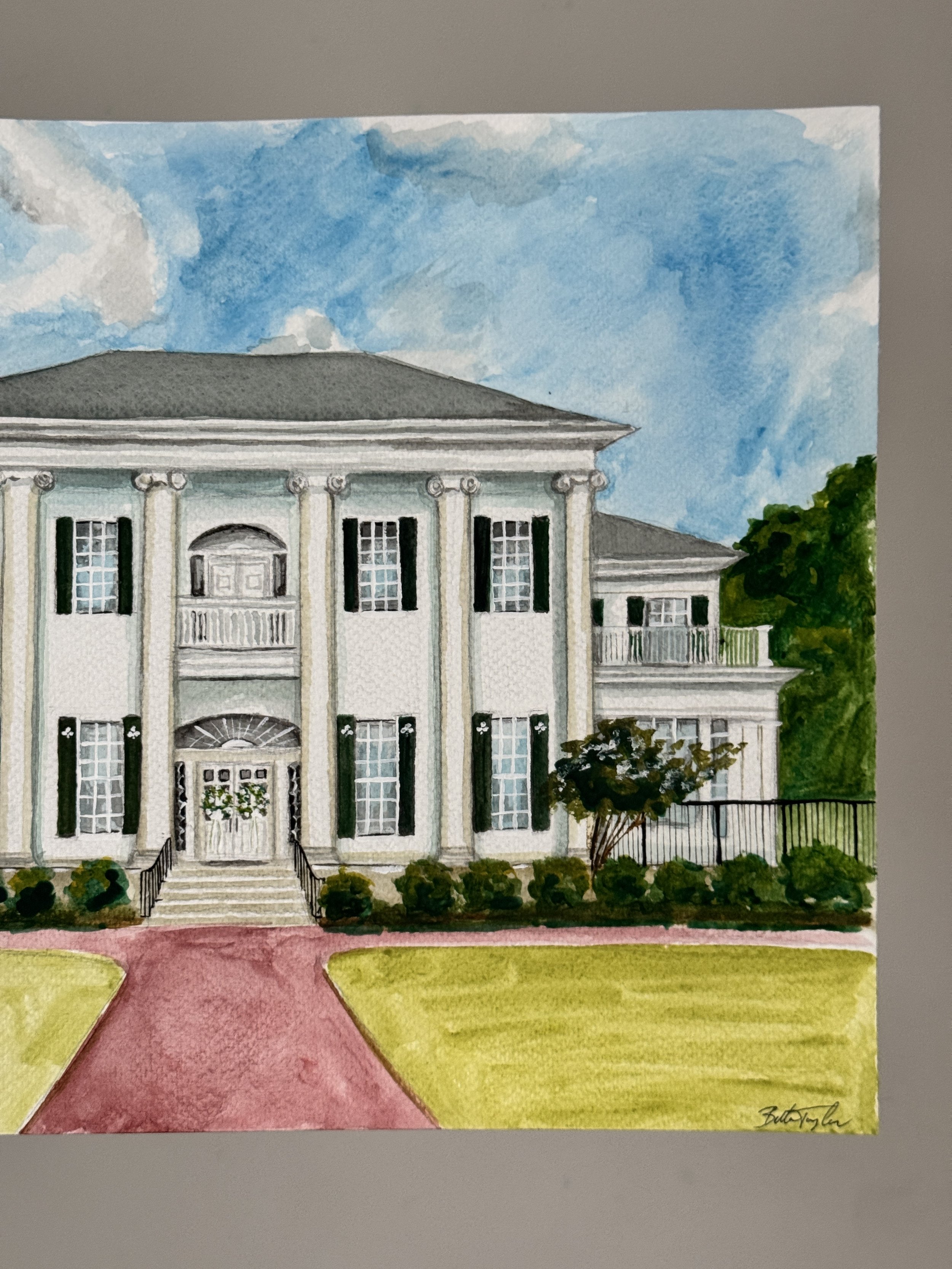 Watercolor painting of a large, white, classical-style house with columns, tall windows, and a front staircase, surrounded by green bushes and trees, under a partly cloudy sky.
