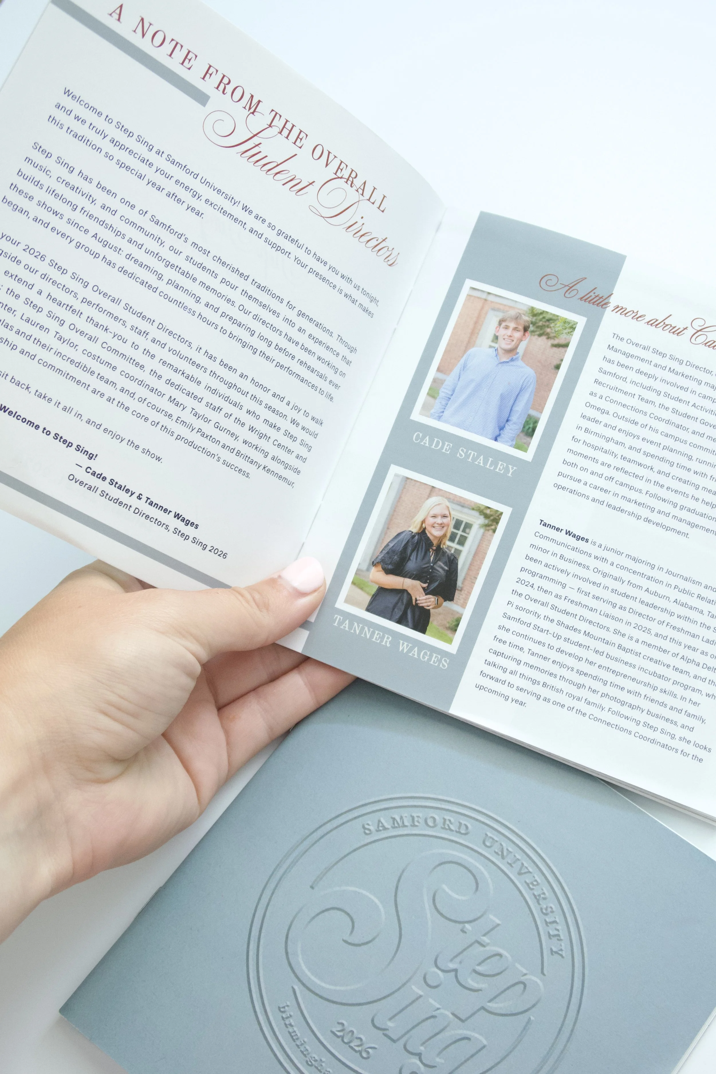 Open booklet for Samford University Step Sing 2026 with a greeting and photo of a young man on the right page, holding a program or booklet with a blue cover and circular logo on the front.