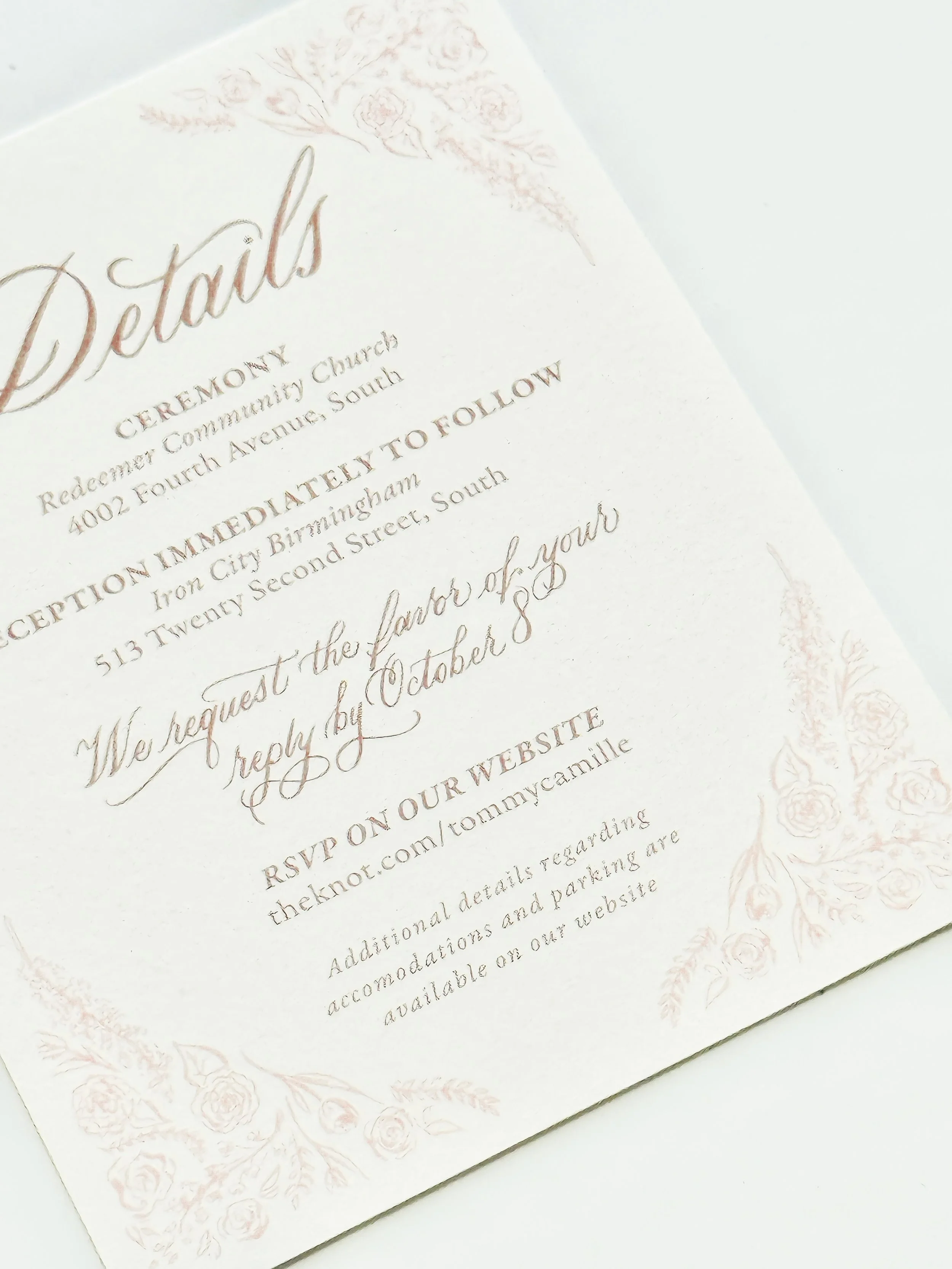 Close-up of a wedding invitation with decorative floral border and elegant script font.