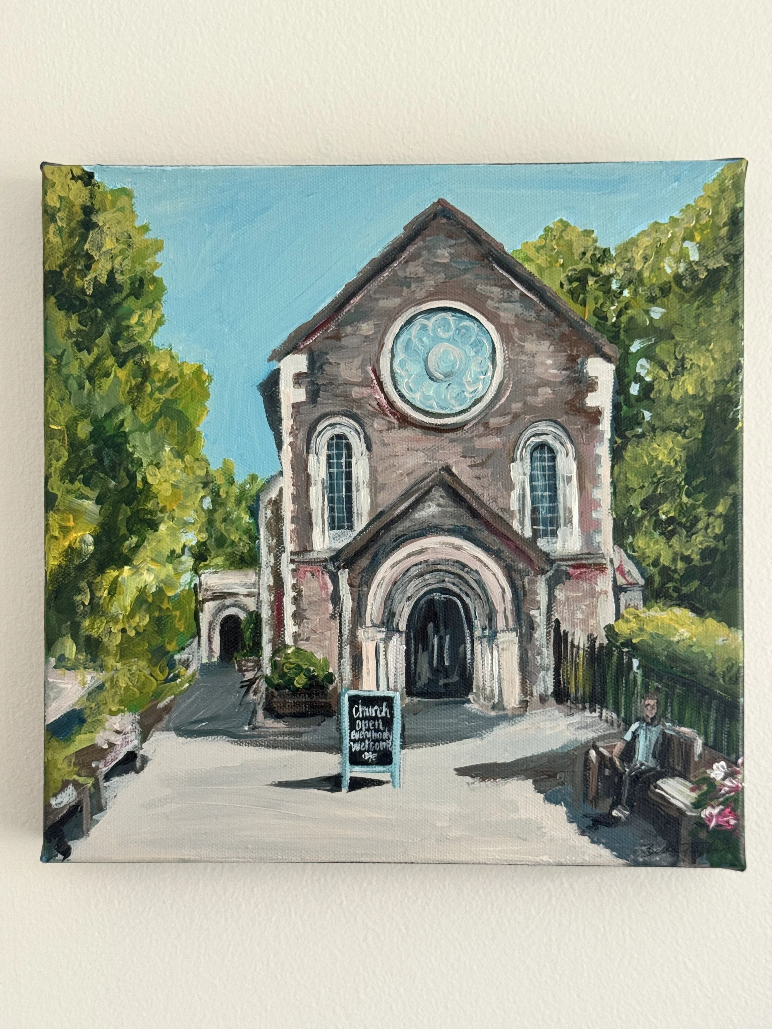 Painting of a church with a large circular window, surrounded by trees, with a sign in front that reads 'church open everybody welcome' and a person sitting on a bench.