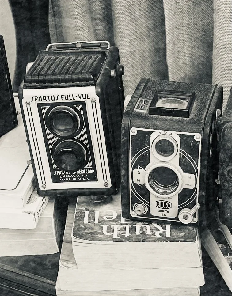 Two vintage box cameras on stacked books