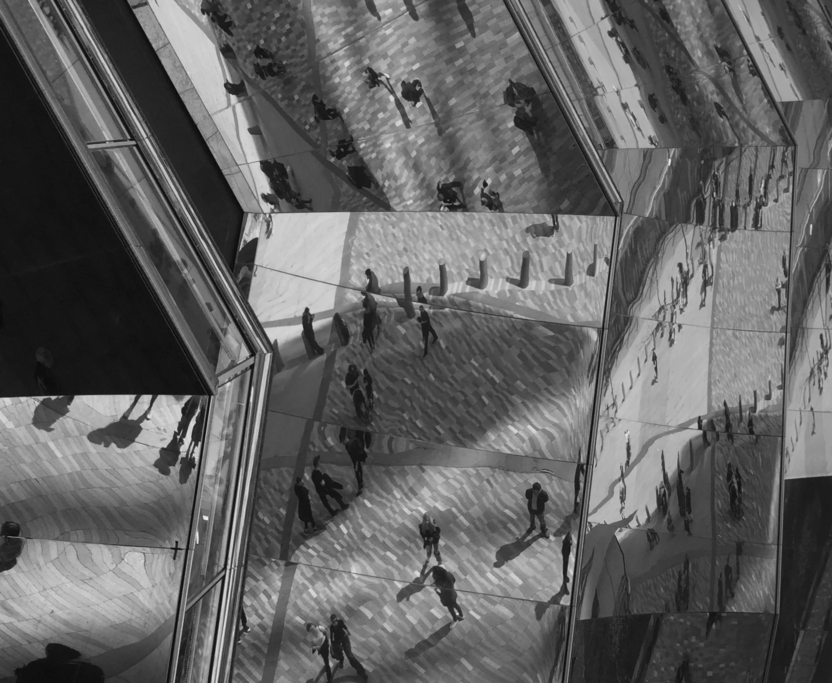 Reflections of people walking on mirrored surfaces creating abstract patterns in black and white.
