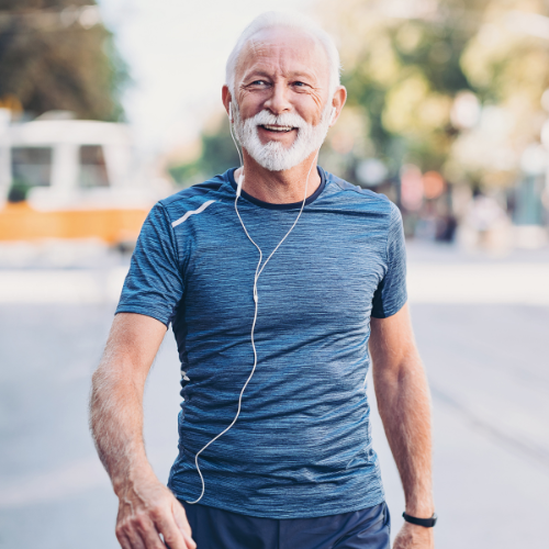 Healthy older gentleman walking outside litening to headphones