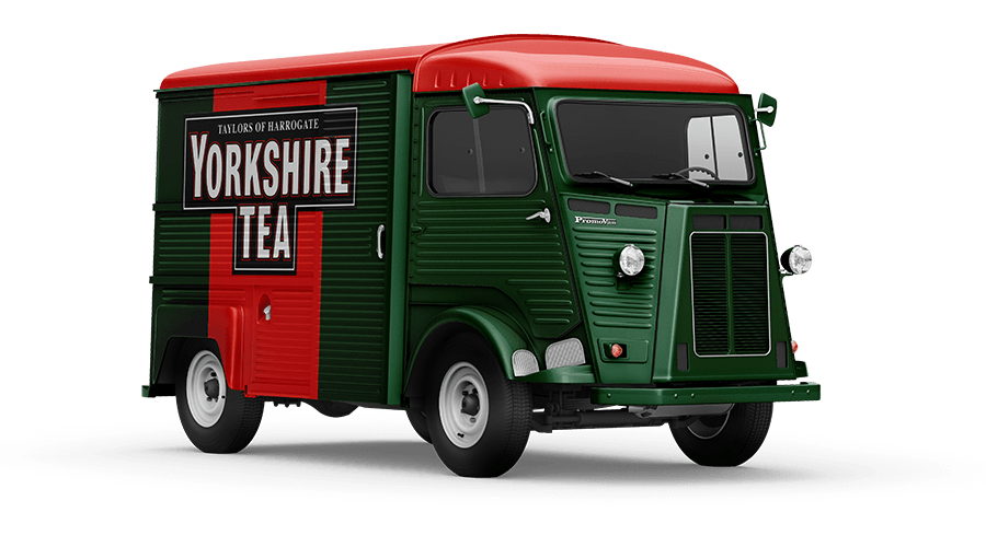 A vintage delivery truck painted in green with a red roof, featuring a large sign on the side advertising Yorkshire Tea from Taylors of Harrogate.