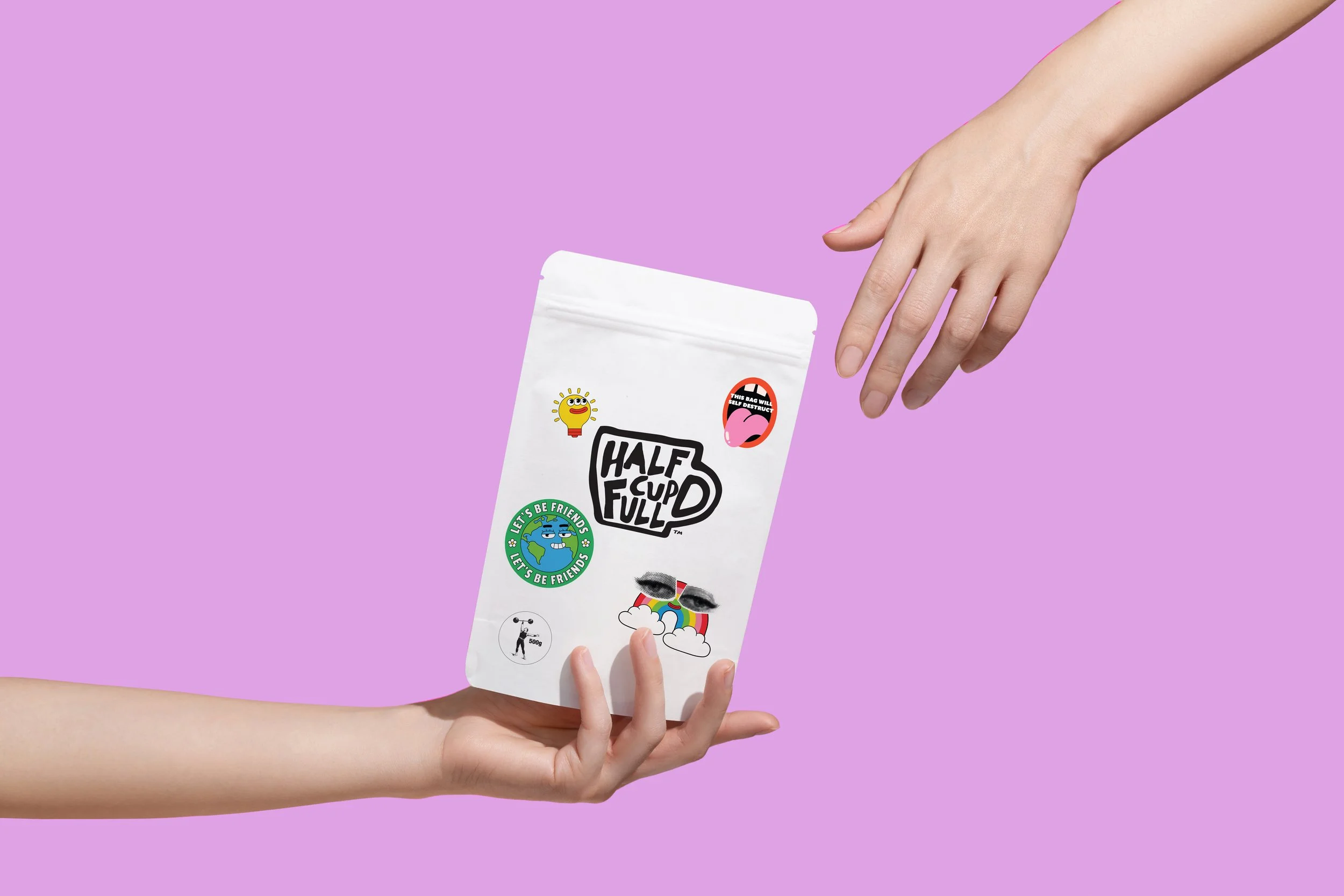 Hand passing a decorated white pouch with stickers, pink background