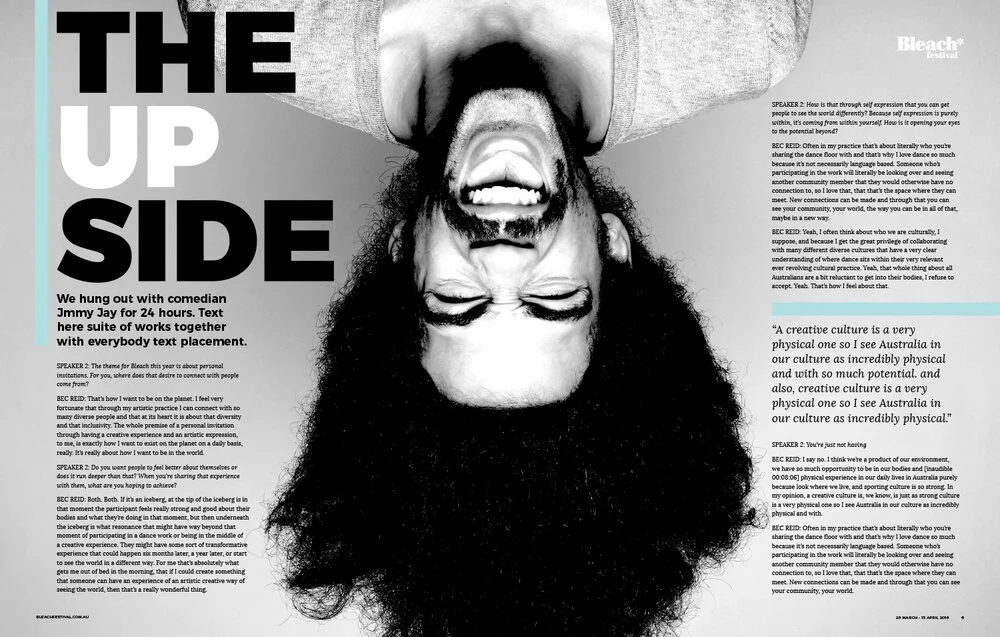 Black and white magazine page with large bold text that says "The Upside" and a close-up of a man with curly hair and beard, upside down, smiling with his mouth open.