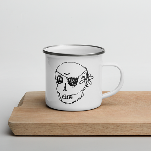 A white enamel mug with a black rim and a skull drawing on the front, placed on a wooden board against a white background.