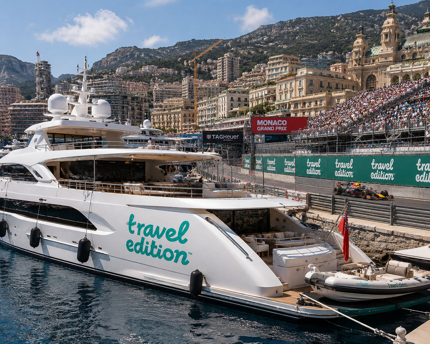 En lyxig yatch som tillhör 'travel edition' är förtöjd vid en kaj i en stad med många höga byggnader och branta klippor i bakgrunden. På andra sidan sjön syns en Formel 1-bil som kör på en racerbana.