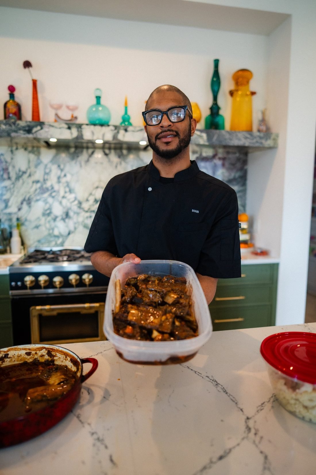 Chef Keenan Brackett holding a container of braised short ribs in a client's kitchen