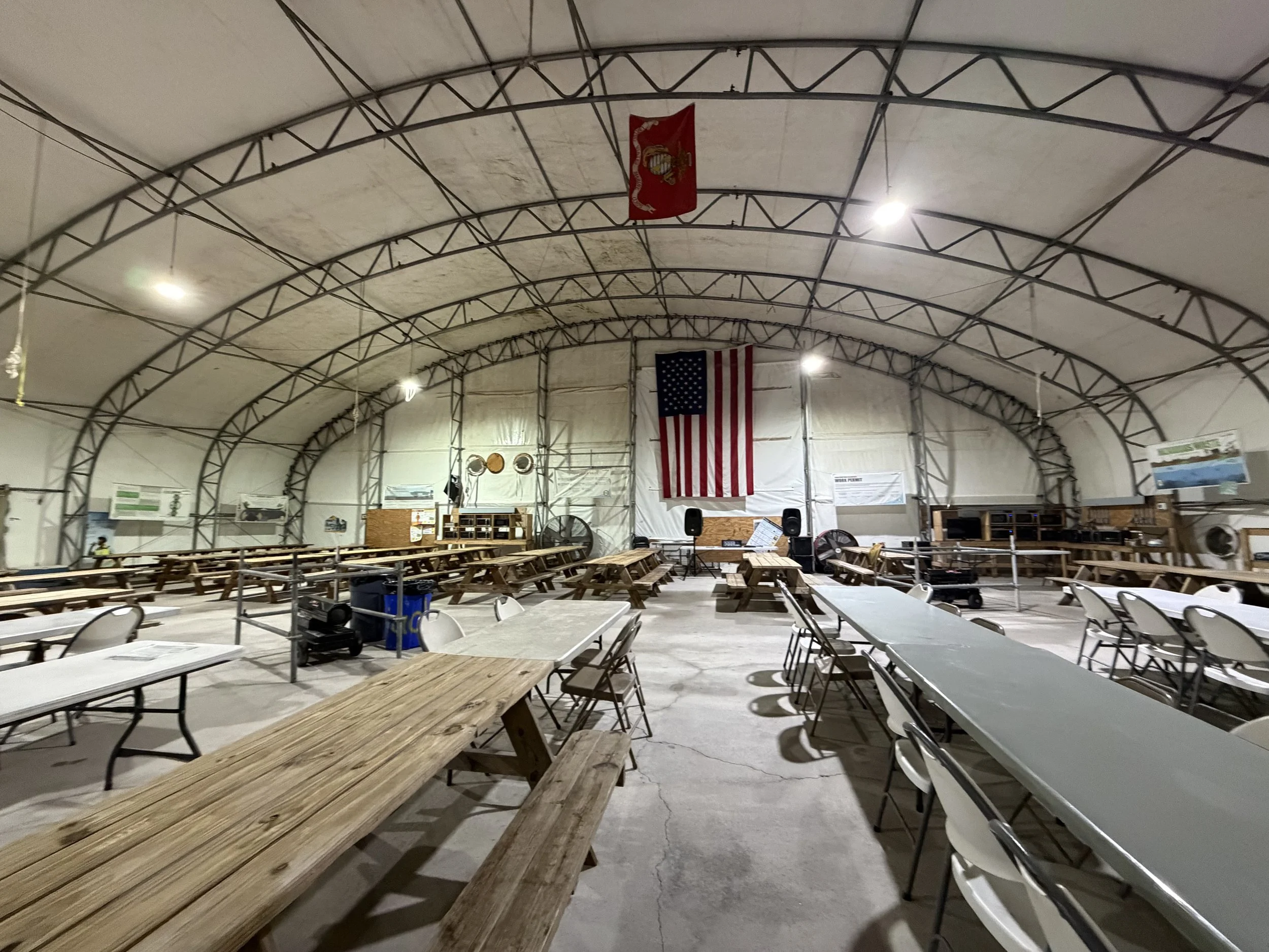 Large indoor space with string lights, American and military flags, folding tables, chairs, and equipment, Commercial  cleaning services