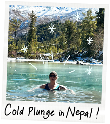 A person swimming and relaxing in a natural spring in Nepal, surrounded by tall green trees and snow-capped mountains in the background, with handwritten text saying 'Cold Plunge in Nepal!' and doodle-like snowflakes around.