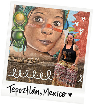 A woman standing in front of a colorful mural of a child's face in Tepoztlán, Mexico.