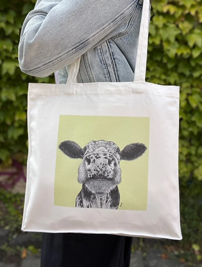 Tote bag featuring a cow illustration against a green background.