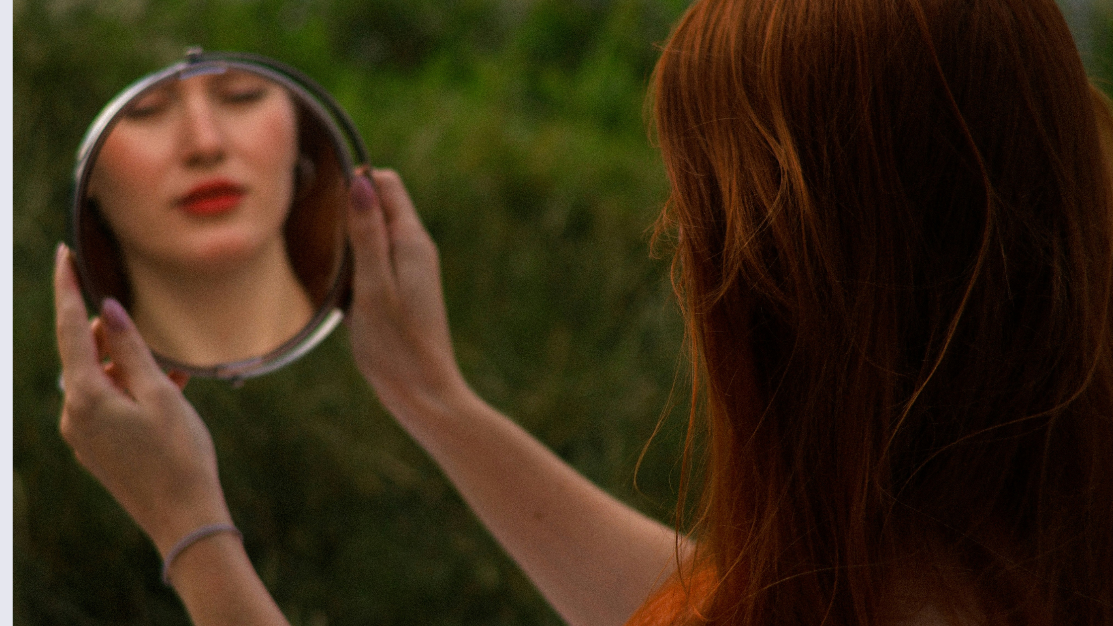 woman holding mirror reflecting her face