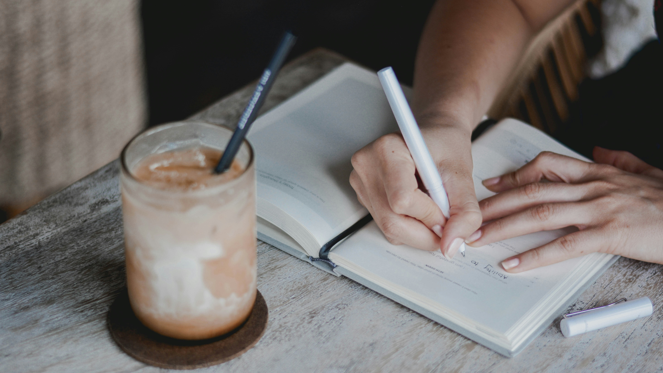 woman writing in a journal with a cup of coffee