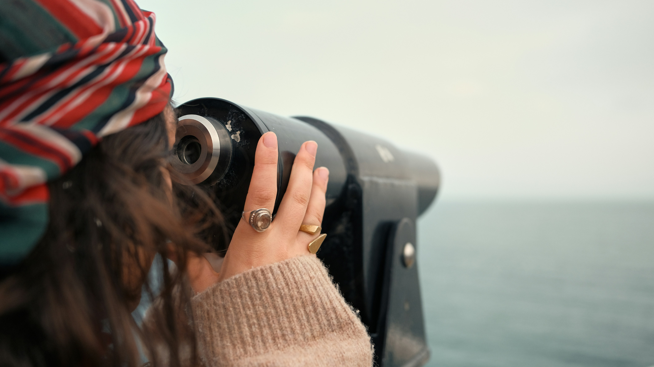 woman looking out of binoculars at the water