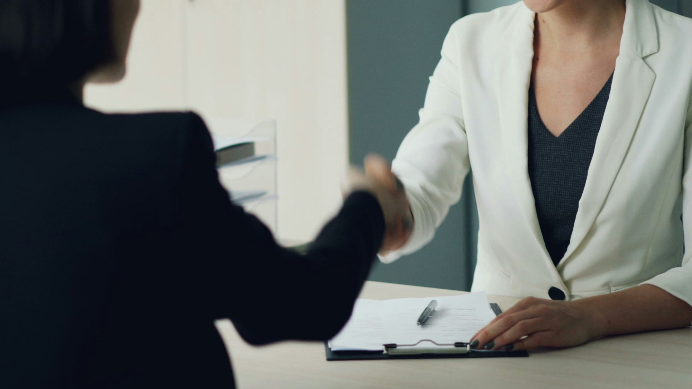 two women shaking hands at desk