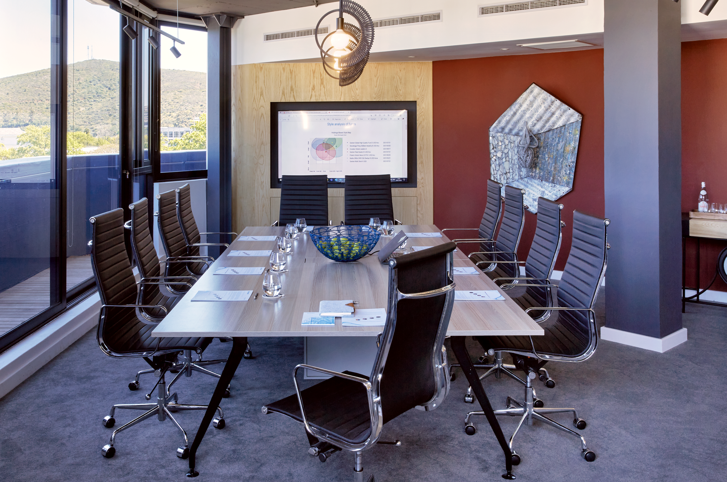 Corporate meeting room with a sculptural mixed-media wall piece installed above a terracotta feature wall, Sanlam Private Wealth Cape Town office