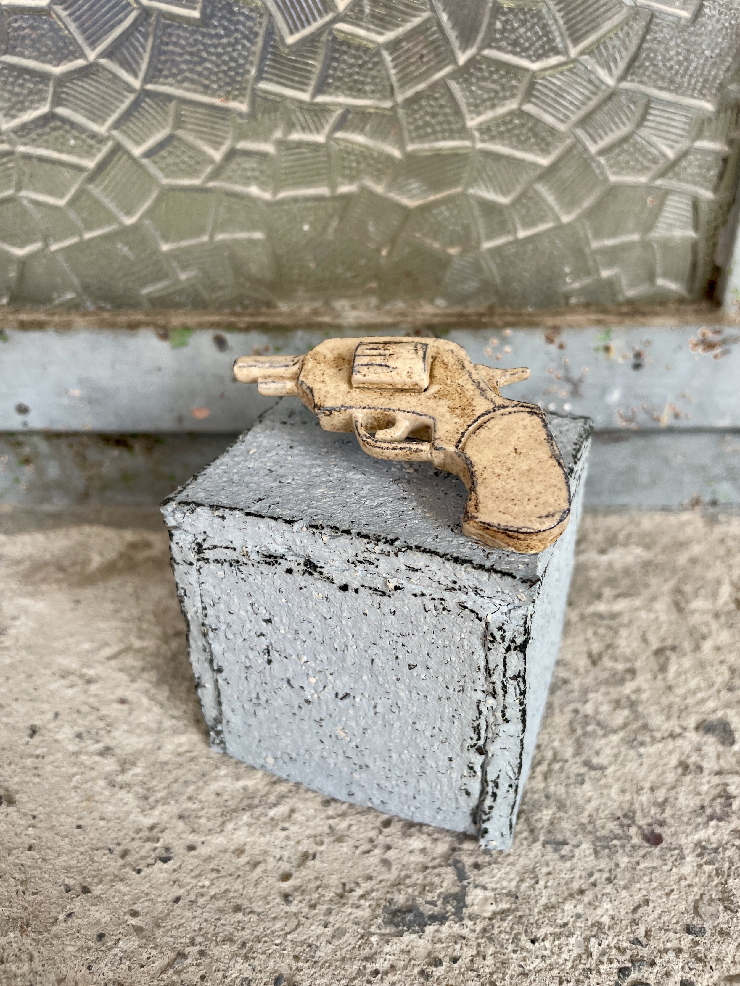 Stoneware mini sculpture of a ceramic gun on aplinth.jpg