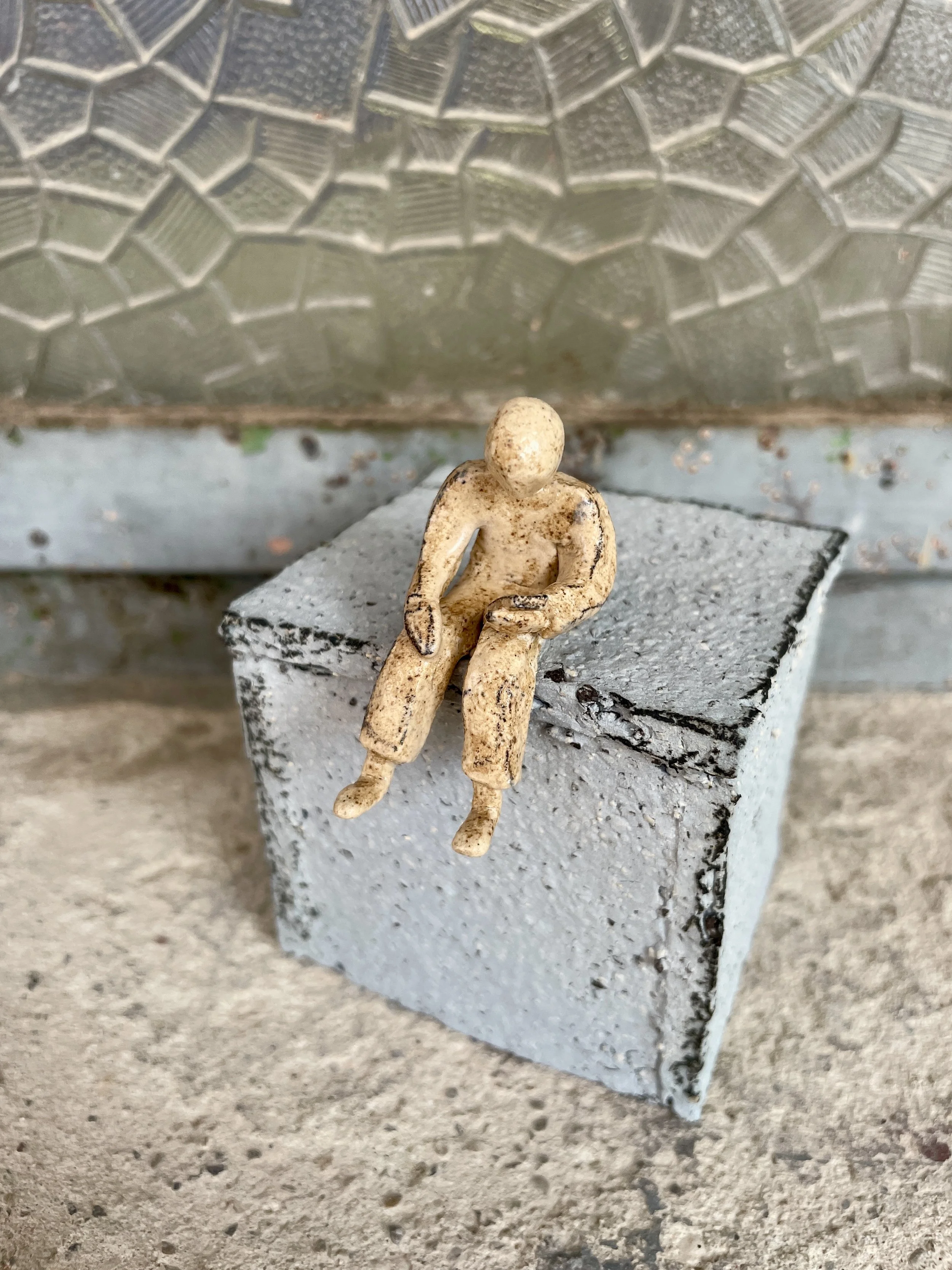 Handmade miniature ceramic sculpture of person sitting and looking at smartphone_00.jpg