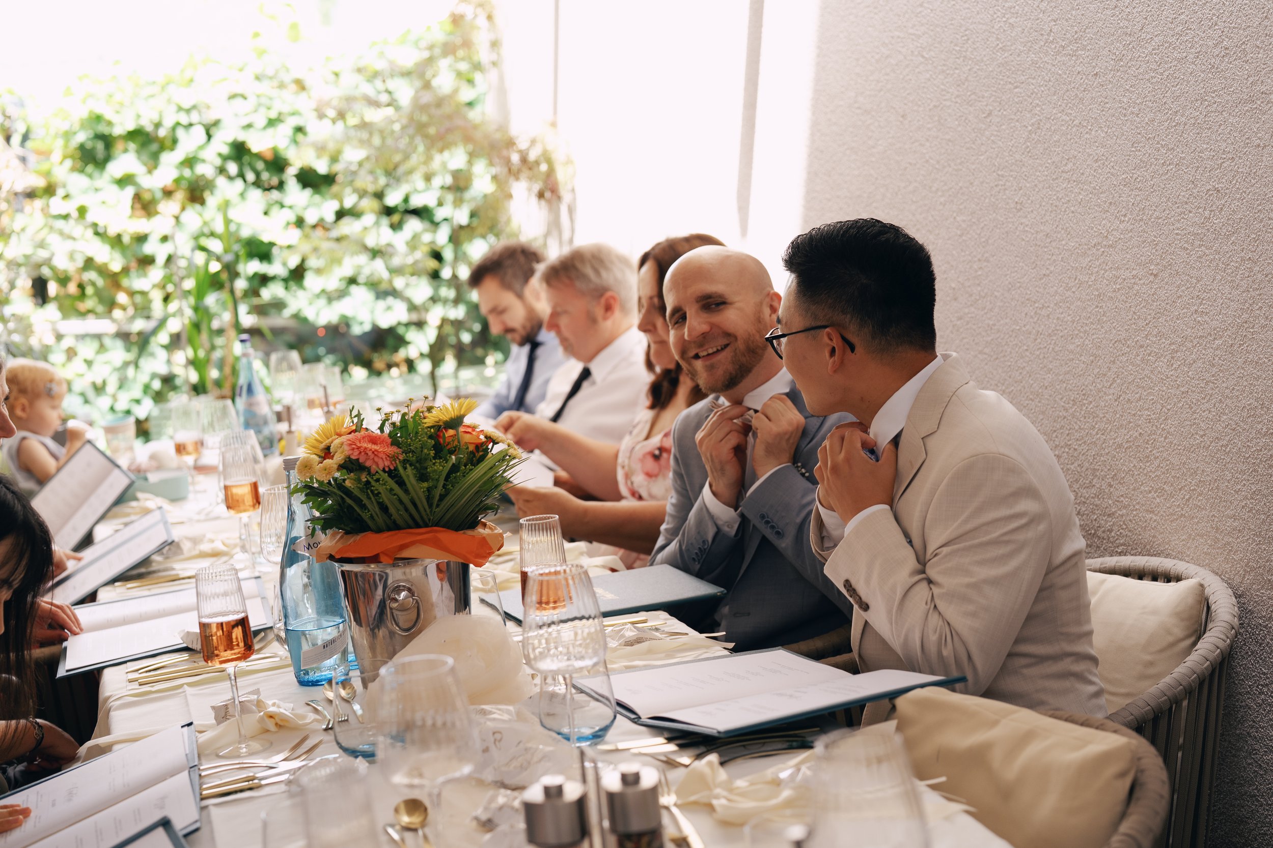 Two grooms listening to a speech during their wedding reception.
