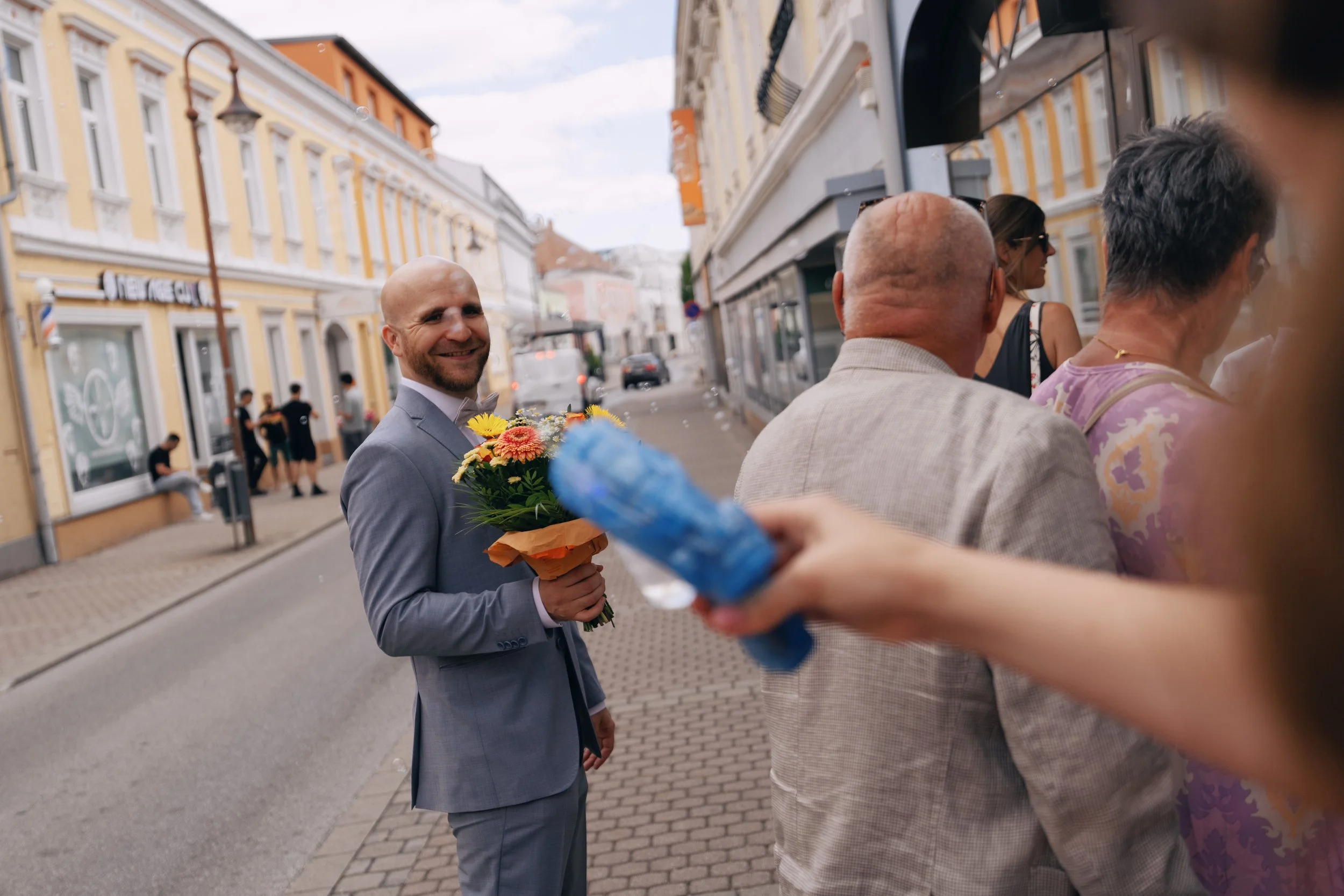 One groom holding the wedding bouquet outside the registry office.