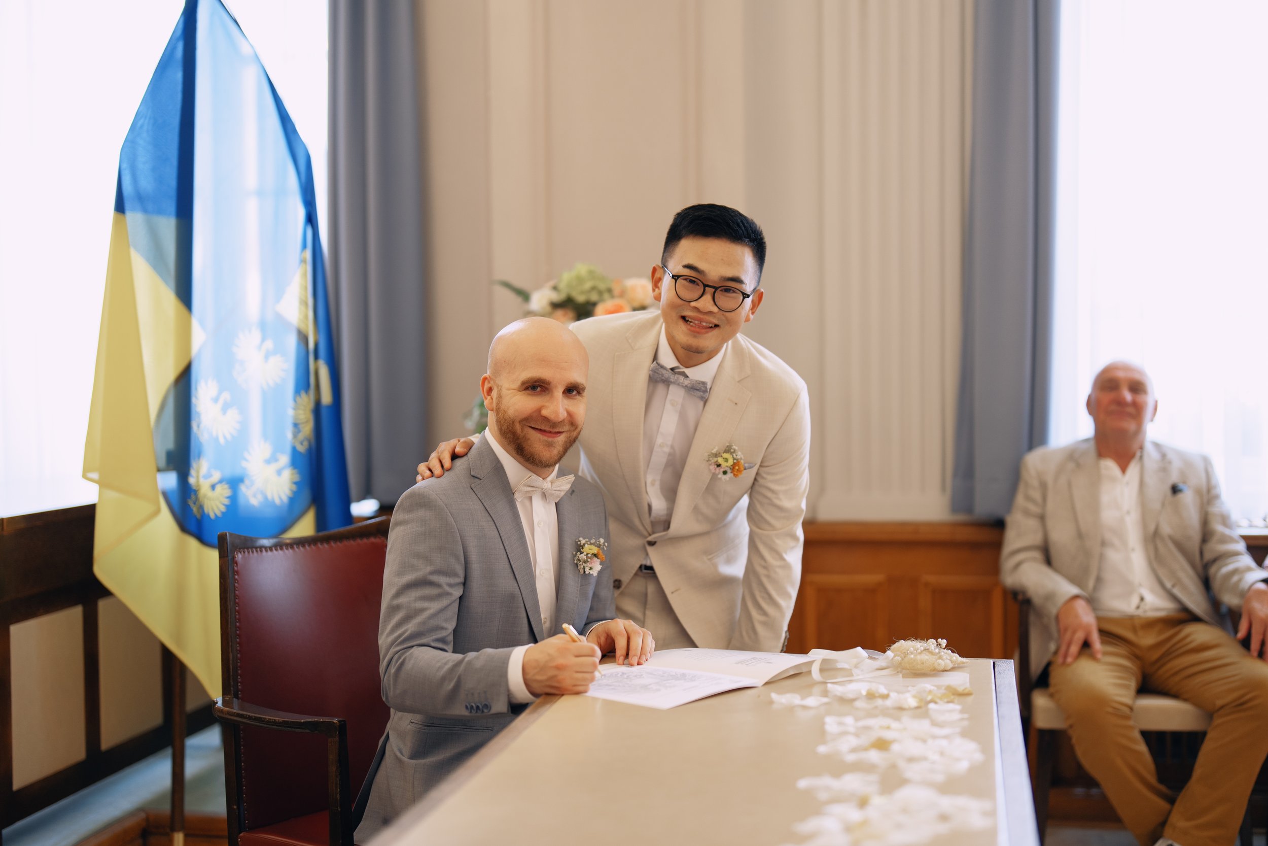 Two grooms signing the marriage certificate during their civil wedding.