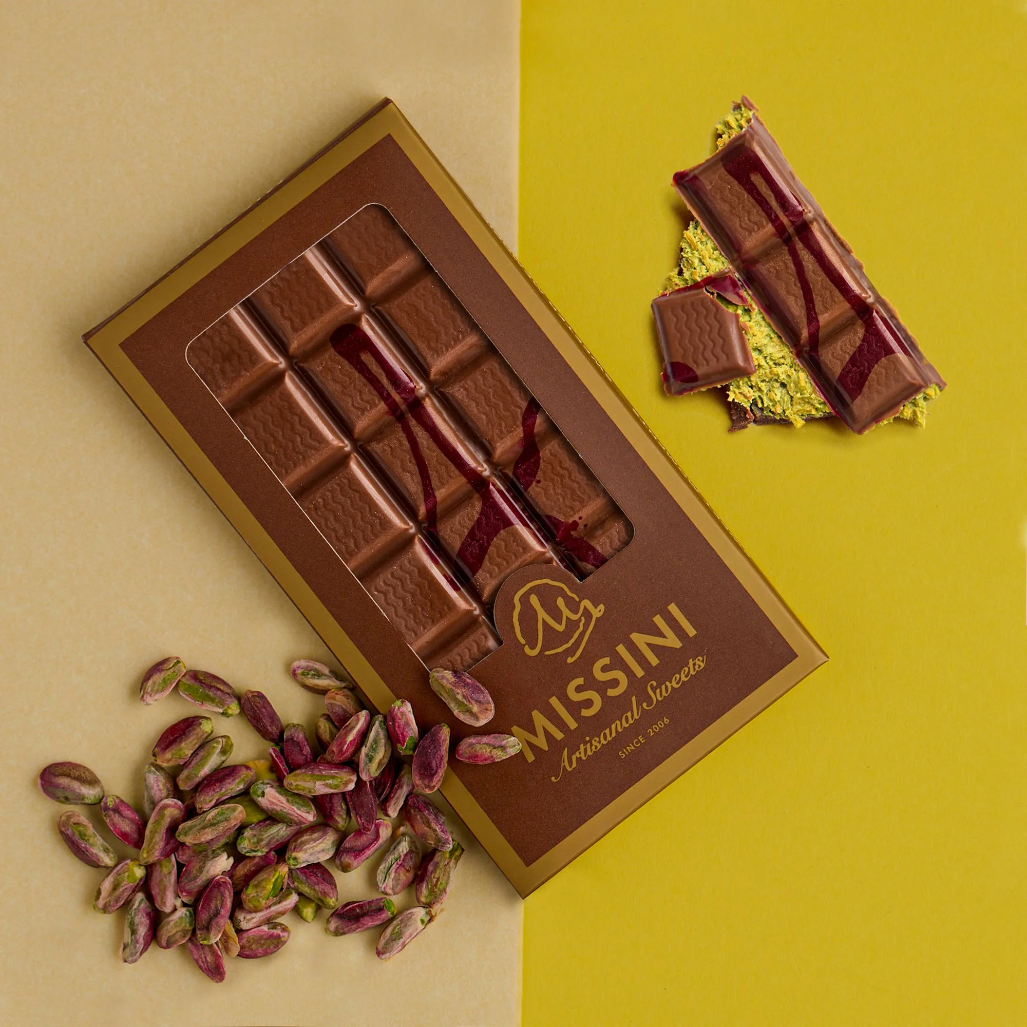 Missini chocolate bar with pistachio and raspberry drizzle, displayed on yellow background with scattered pistachios.