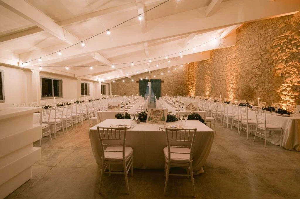 The Limonaia at Castello di Galbino set for a wedding dinner, with long tables beneath string lights.
