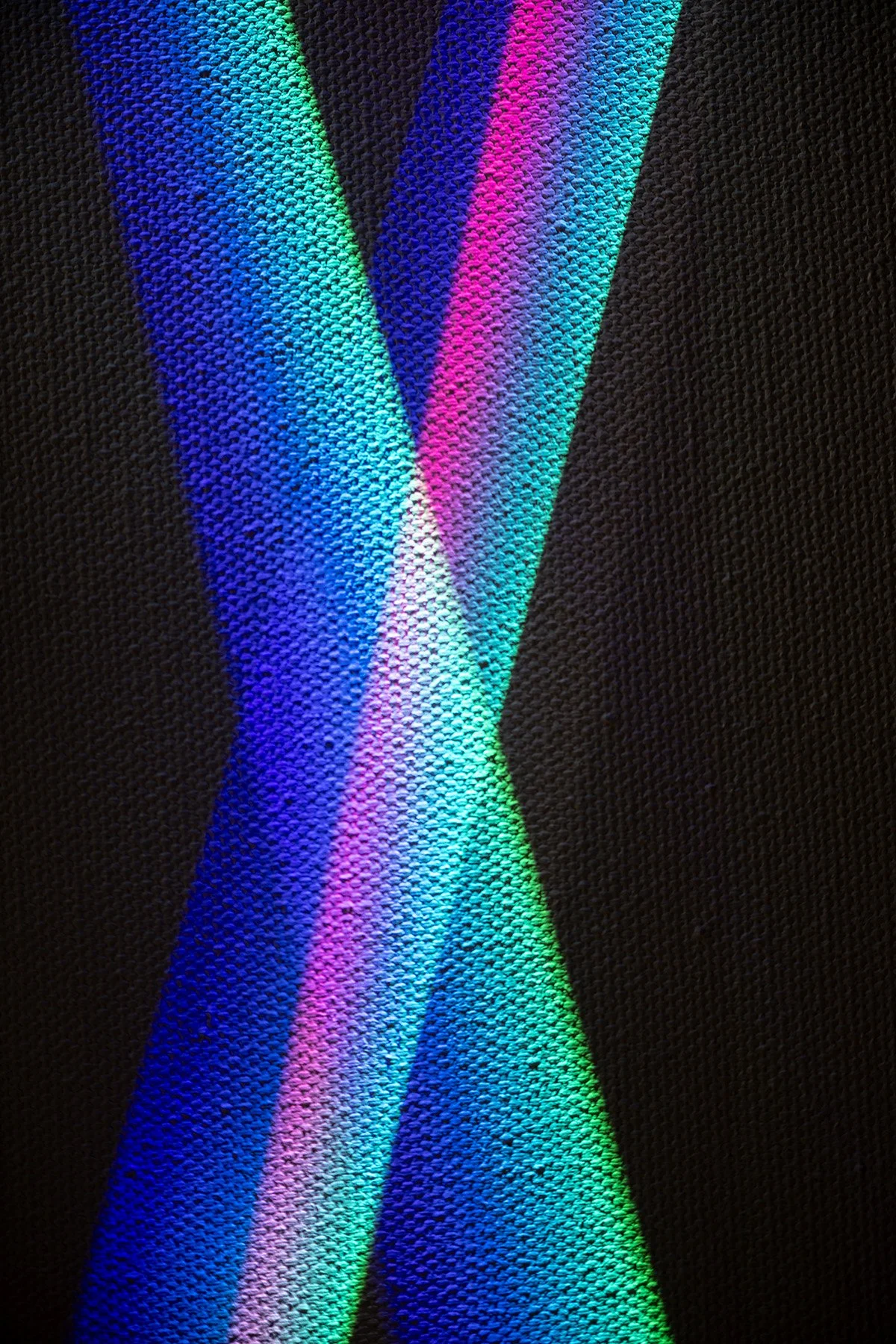 Close-up of textured black fabric with vibrant blue, turquoise, pink, and green stripes