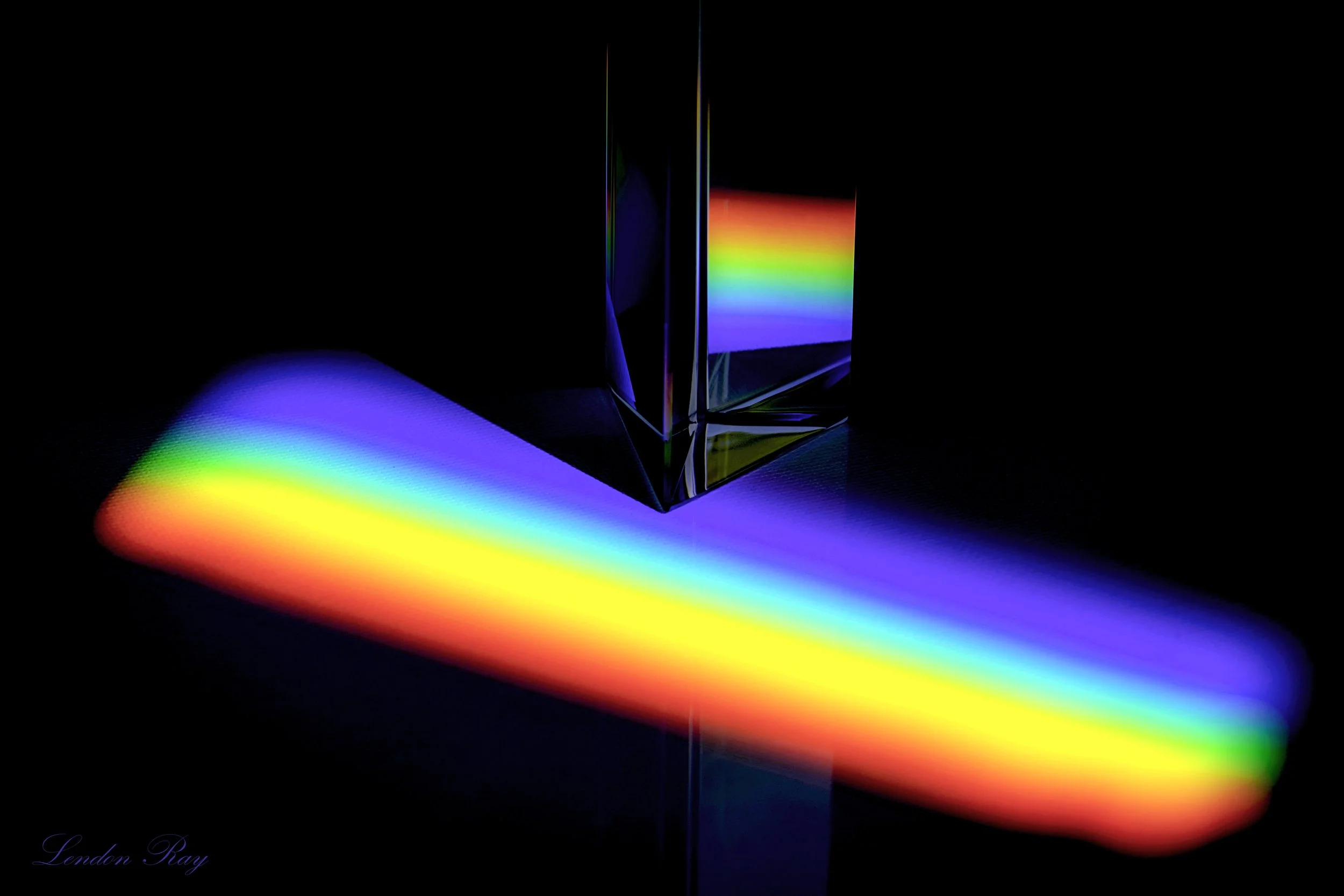 A glass prism with light passing through, creating a rainbow spectrum of colors reflected on a dark background.