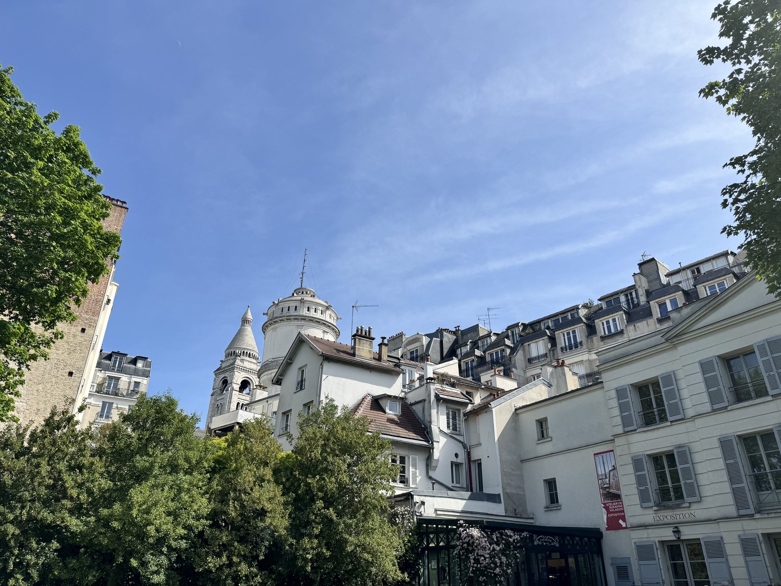 Blick auf eine Stadt mit historischen Gebäuden, Türmen und einer klaren blauen Himmel mit leichter Bewölkung.