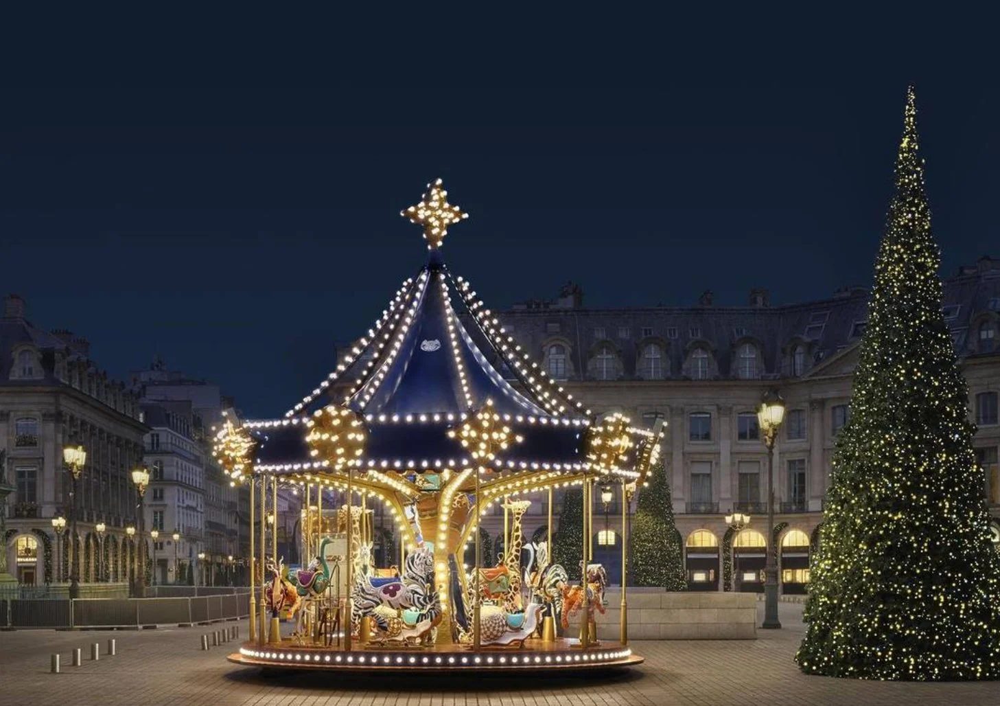 Beleuchtetes Weihnachtskarussell mit Pferdefiguren und großem Weihnachtsbaum auf einem festlich dekorierten Platz bei Nacht