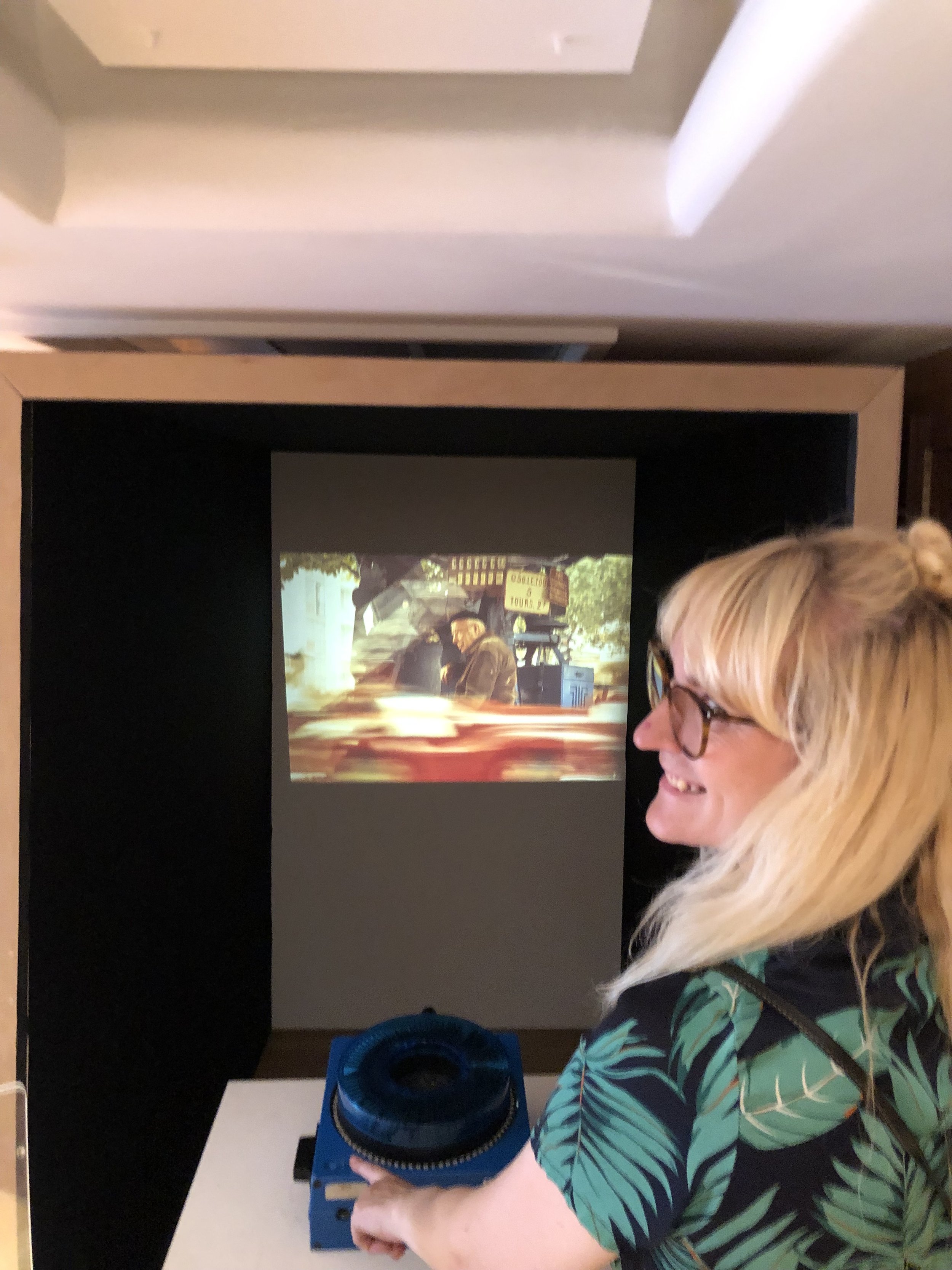 Viele Menschen beobachten eine Präsentation oder einen Film auf einer Leinwand in einem dunklen Raum.