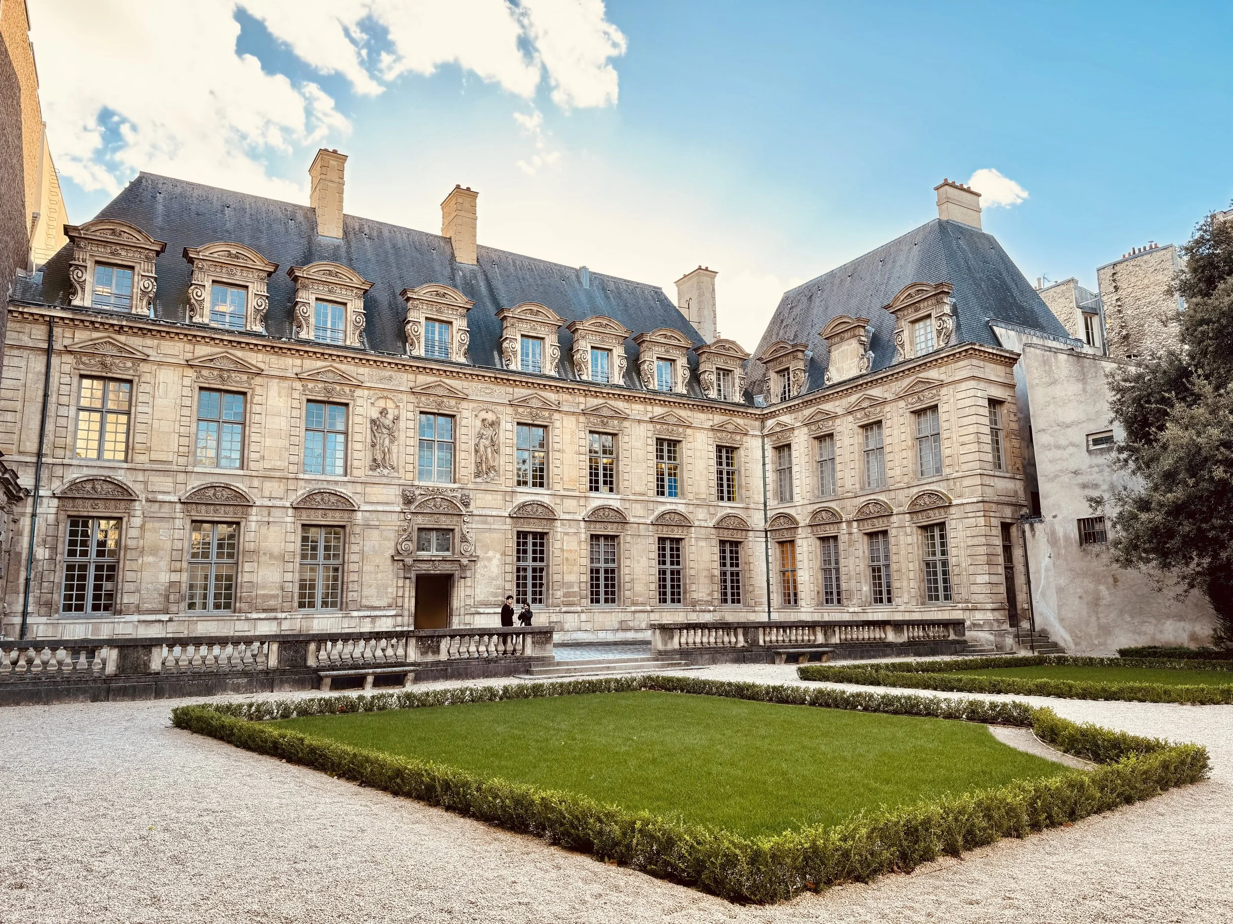 Il de France style historic French chateau with ornate stone architecture and a manicured garden in the foreground.