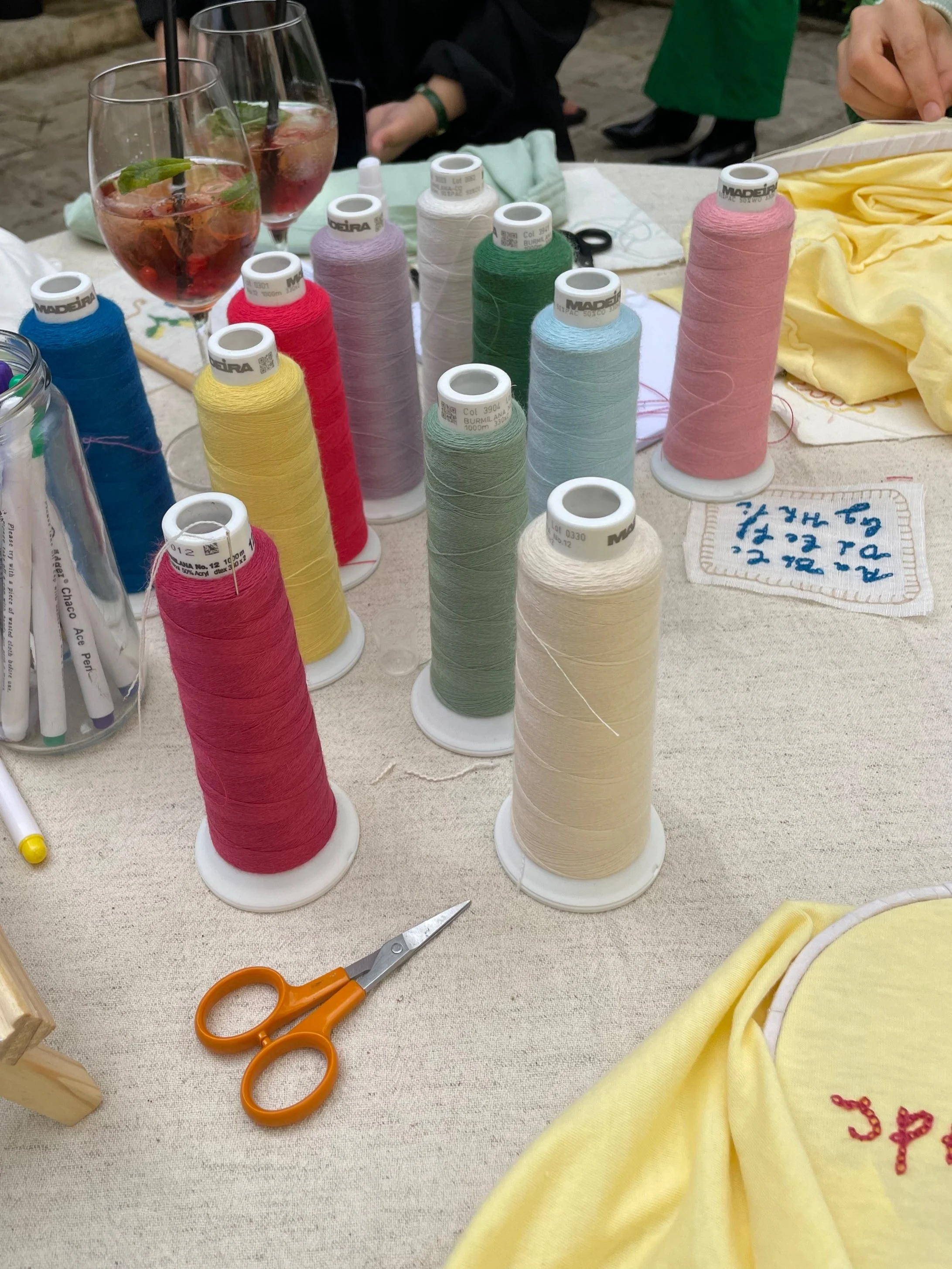 Several spools of colorful thread, small scissors, and embroidery materials on a table.