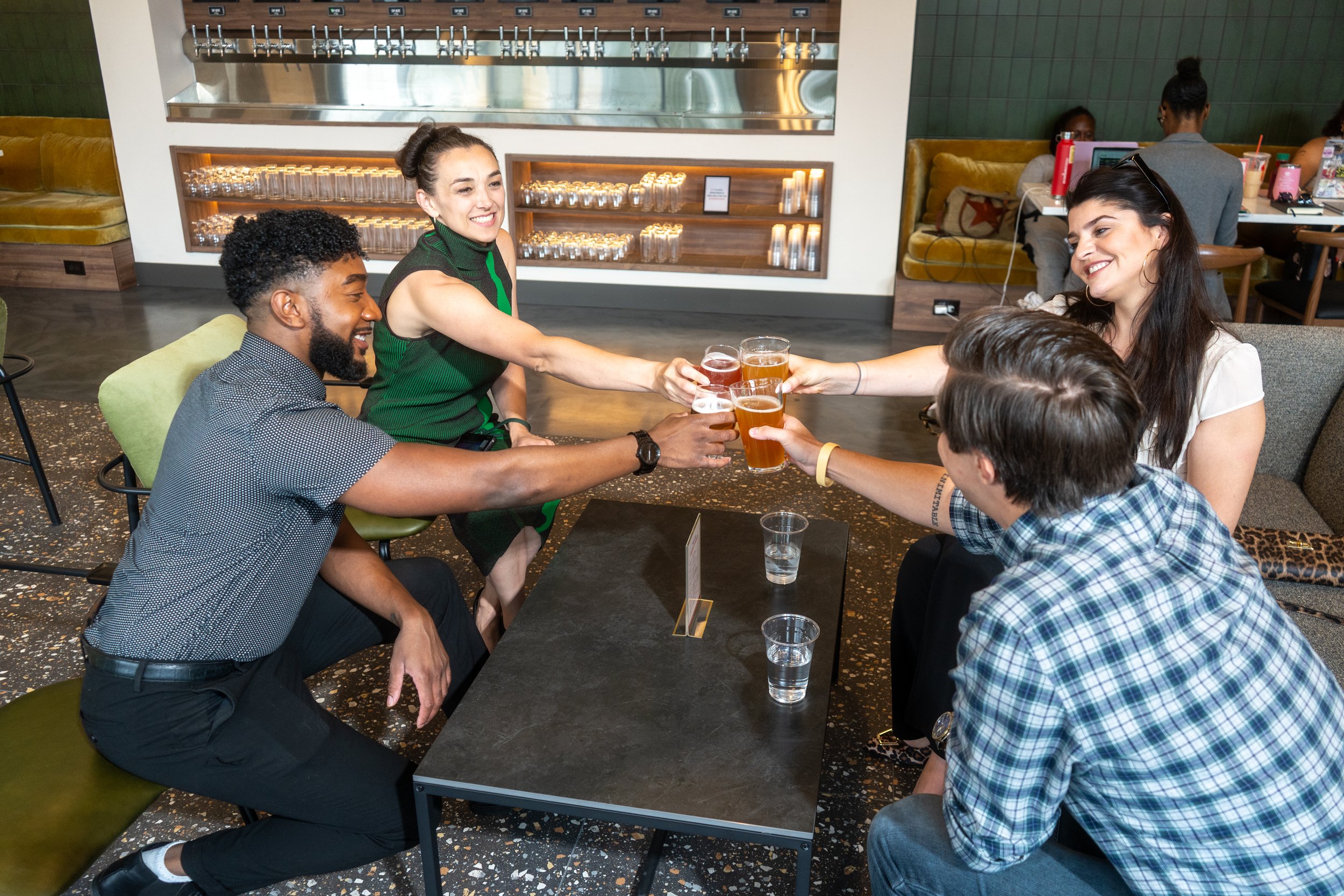 Group of five friends raising glasses of beer in a toast at a bar or restaurant