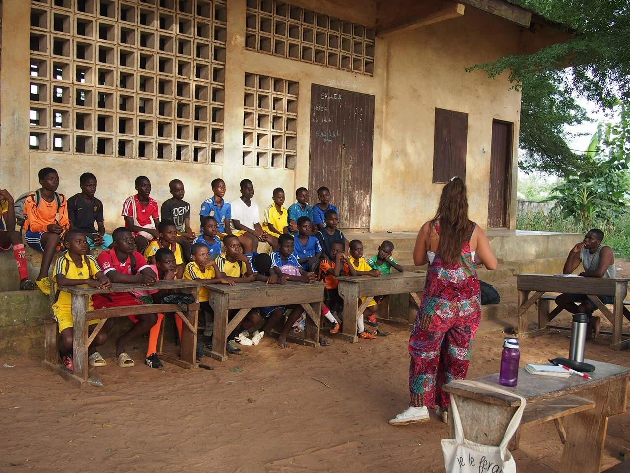 Laura en atelier de sensibilisation avec une vingtaine d'enfants assis à l'extérieur de la salle de classe