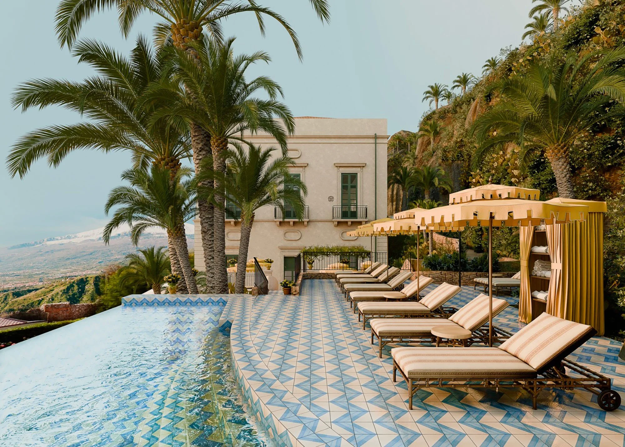 A luxury outdoor pool area with striped lounge chairs, beige cabanas, tall palm trees, and a hillside with greenery in the background.