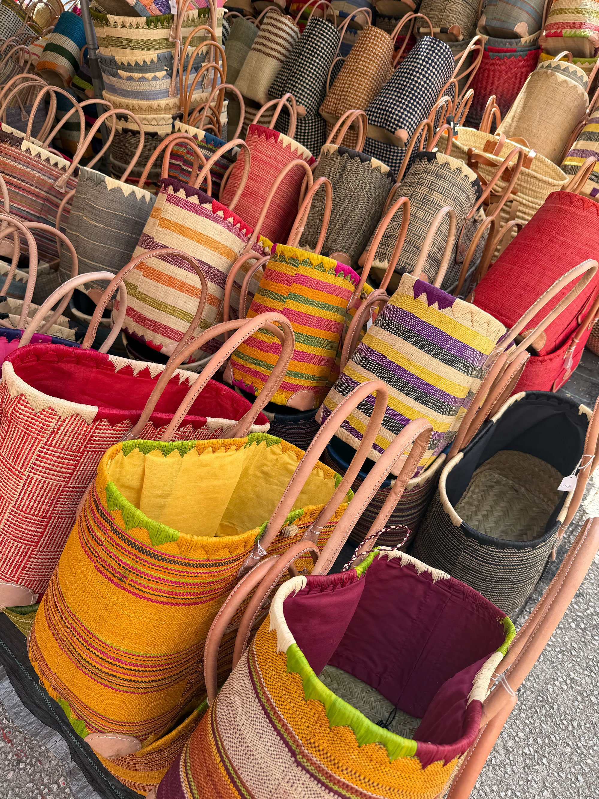 Colorful woven bags displayed in a store, with various patterns and textures, some with handles and some with open tops.