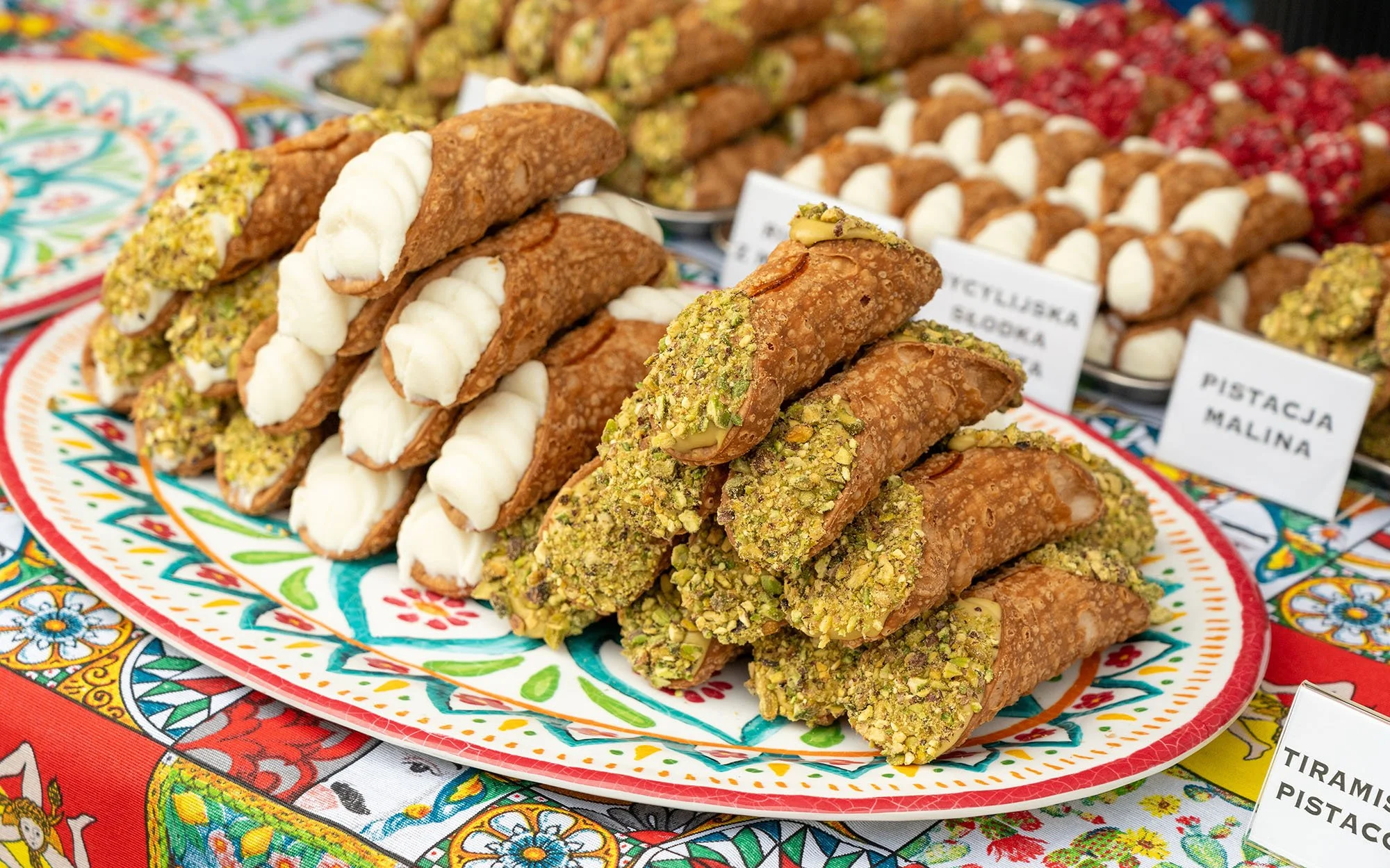 Traditional Mexican trompo-shaped pastries topped with different nuts and creams, displayed on a colorful decorative plate.
