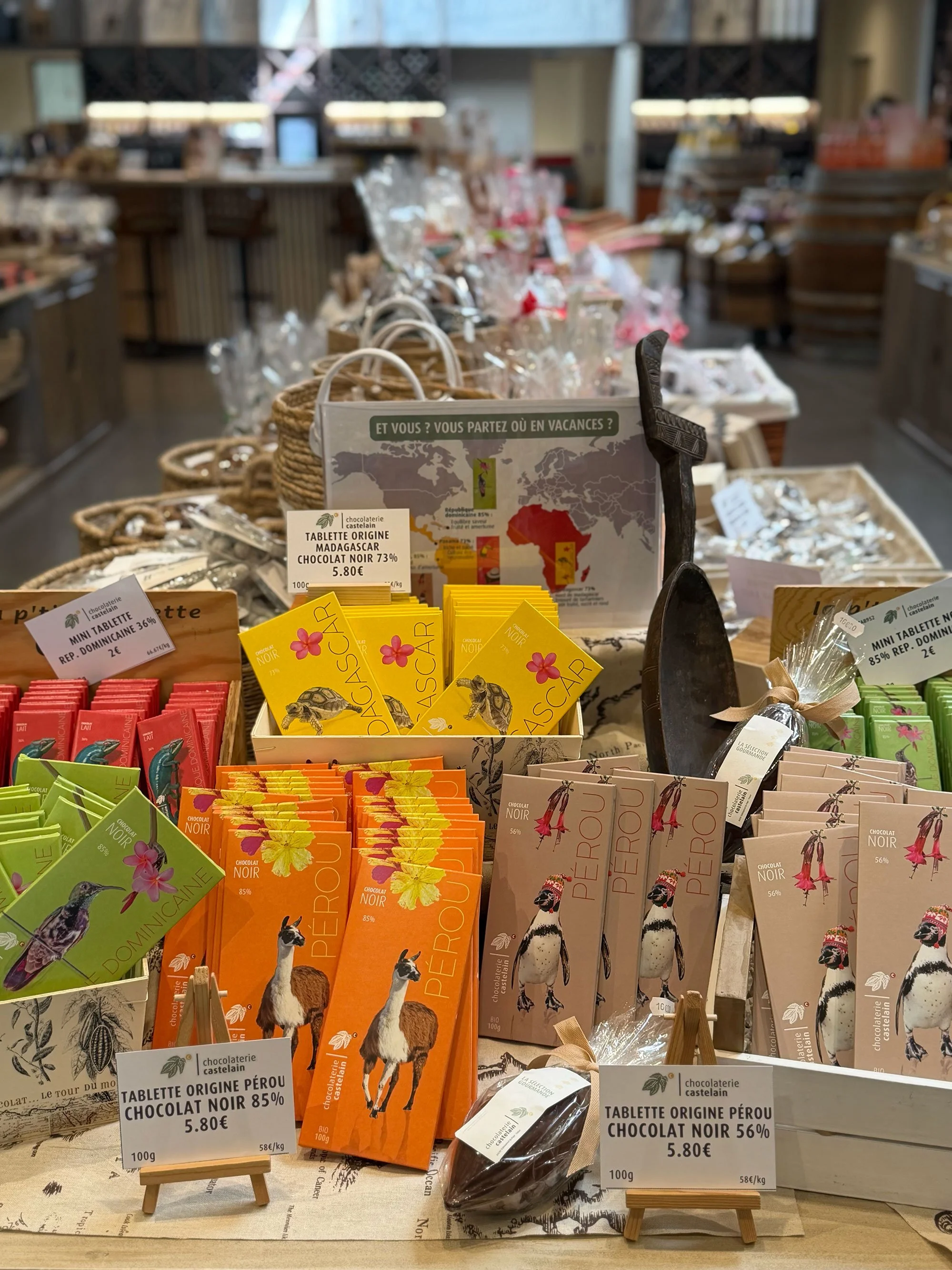 Display of various chocolates at a store, including Peruvian origin dark chocolate with images of a llama and a bird, and several colorful packages in the foreground.