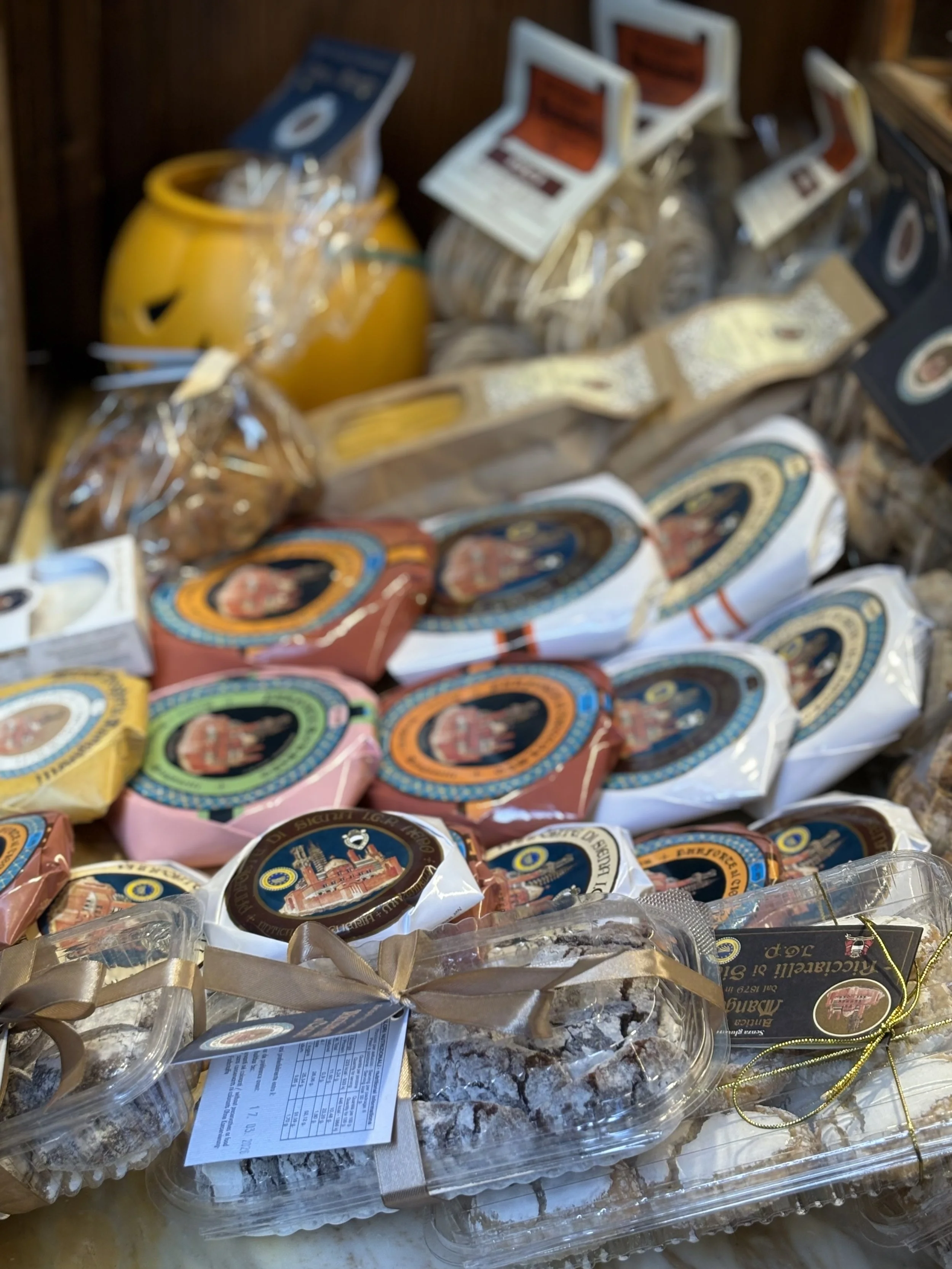 Assorted Italian cheeses, including slices and blocks, with colorful packaging and labels, arranged on a wooden surface.