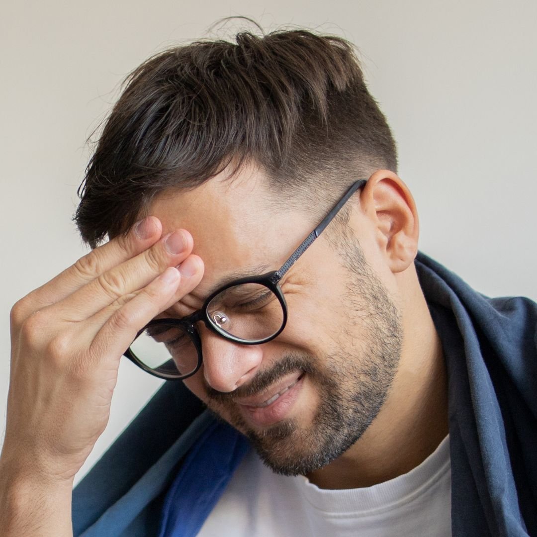 Man holding his head with one hand with glasses on