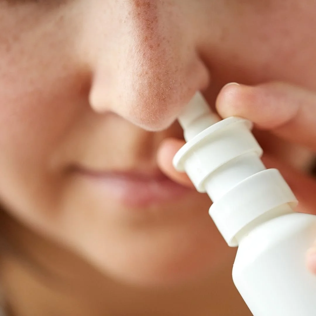 person using a nasal spray to try and clear blocked nose